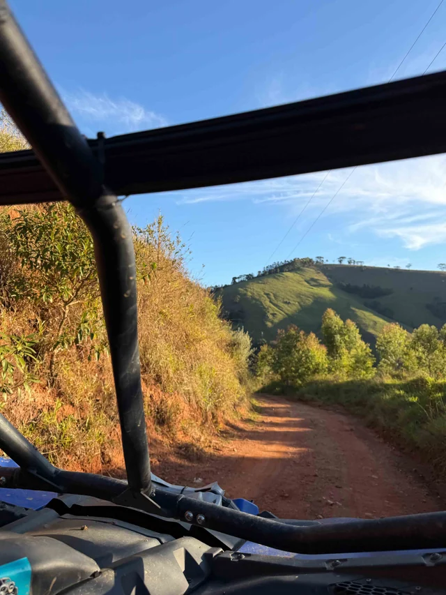 Trilha vista de dentro do UTV com montanhas ao fundo.