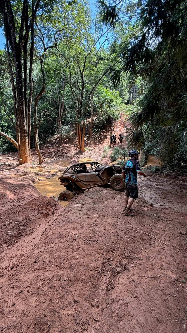 UTV em trecho de lama dentro de uma trilha arborizada.