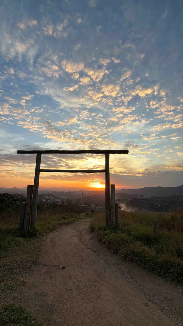 Trilha em mirante com pôr do sol e estrutura de madeira.