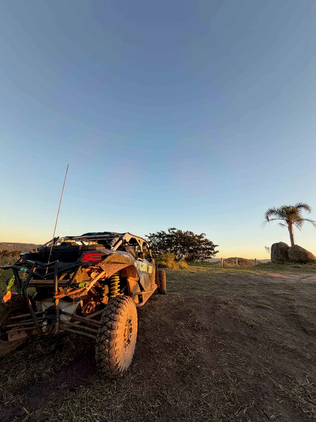 UTV parado próximo ao pôr do sol em estrada de terra.