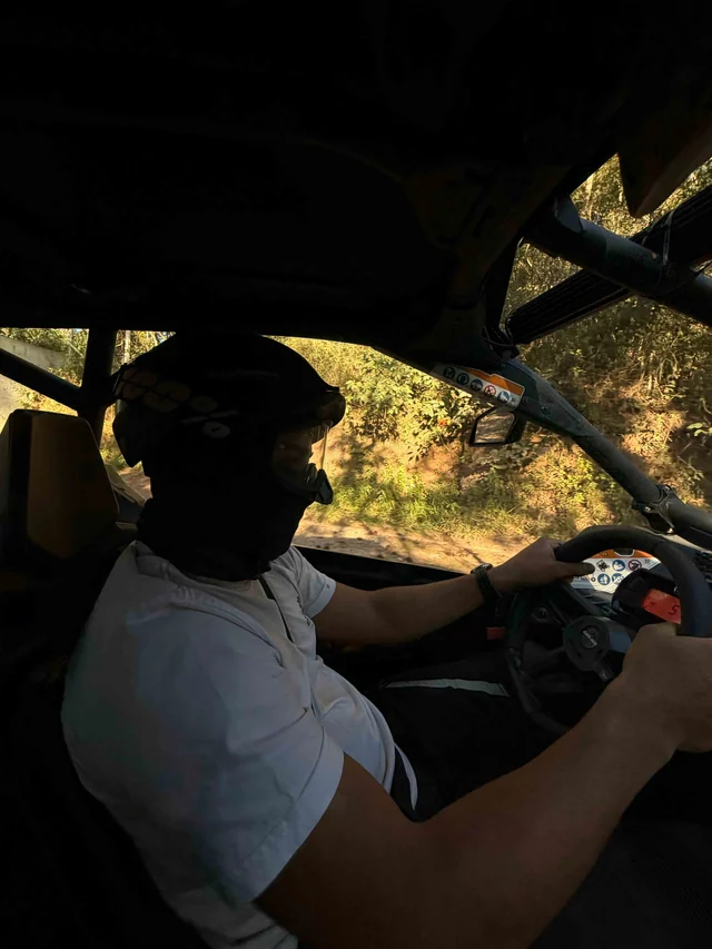 Piloto no interior do UTV em trecho sombreado da trilha.