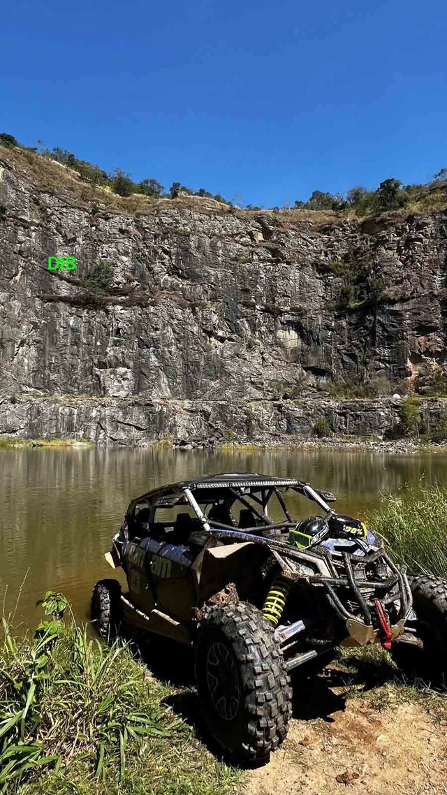 UTV diante de paredão e lago em área de parada.
